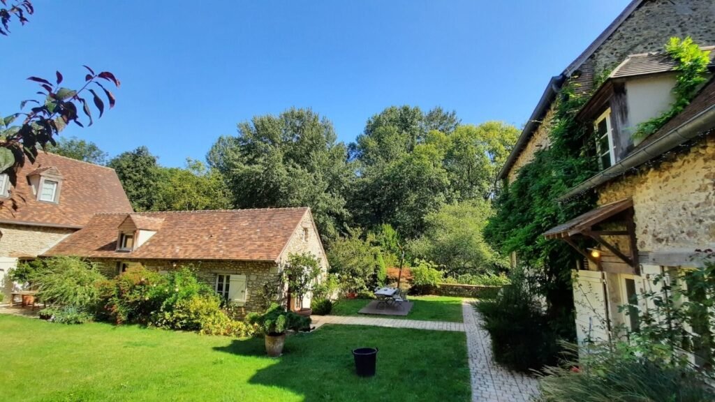 Façade du Moulin de Lonceux entourée de verdure en Eure-et-Loir